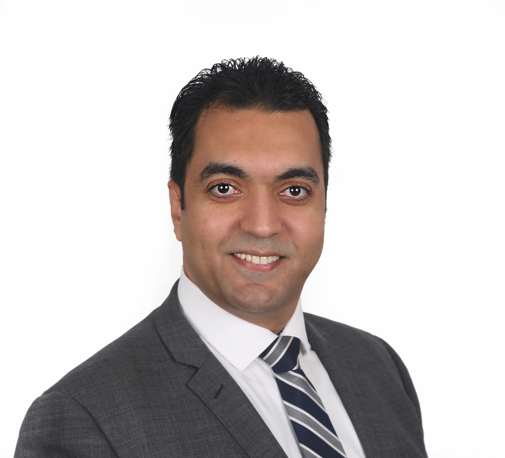 Mohamed Elalfy - he is wearing a grey suit, a white shirt, and a black and grey striped tie