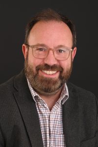Russell Hobby, Non-Executive Director - he is wearing a dark suit and a checkered shirt