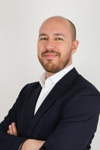 Mr Chris-Macdonald, Consultant Chris-Macdonald Plastic and Reconstructive Surgeon, in a black suit and a white shirt.